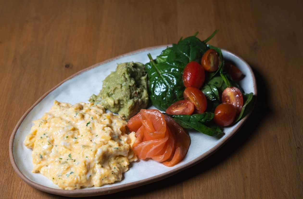 Scrambled eggs with guacamole and salad with salmon