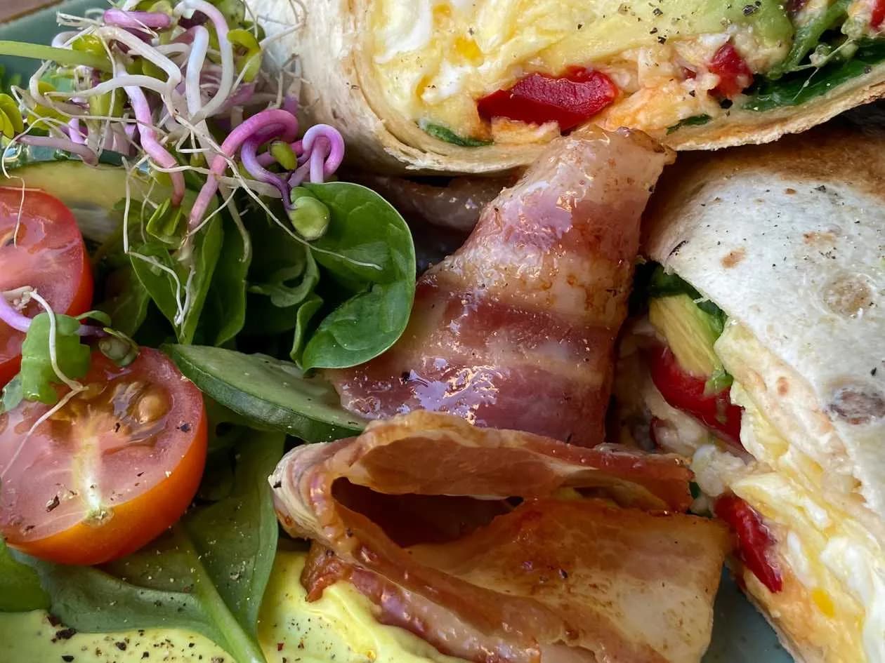 Breakfast tortilla with scrambled eggs, awocado, bacon, salad & aioli