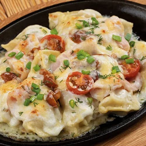 Домашние пельмени, запеченные под сливочным соусом с ветчиной и опятами