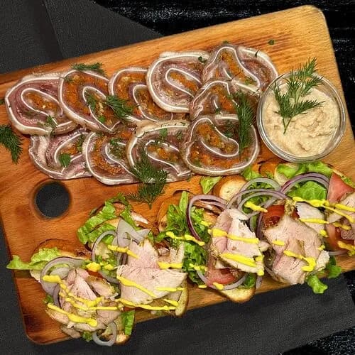 Доска с рулетом из ушей и бужениной на тостах