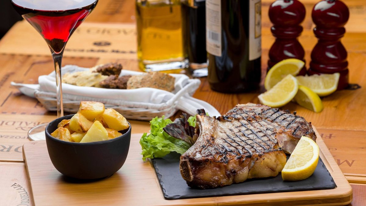 Fiorentina alla griglia servita con patate dorate al rosmarino e sale grosso