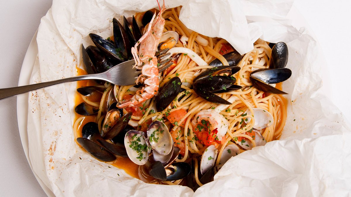 Spaghetti ai frutti di mare in cartoccio di pergamena con pomodorini e basilico